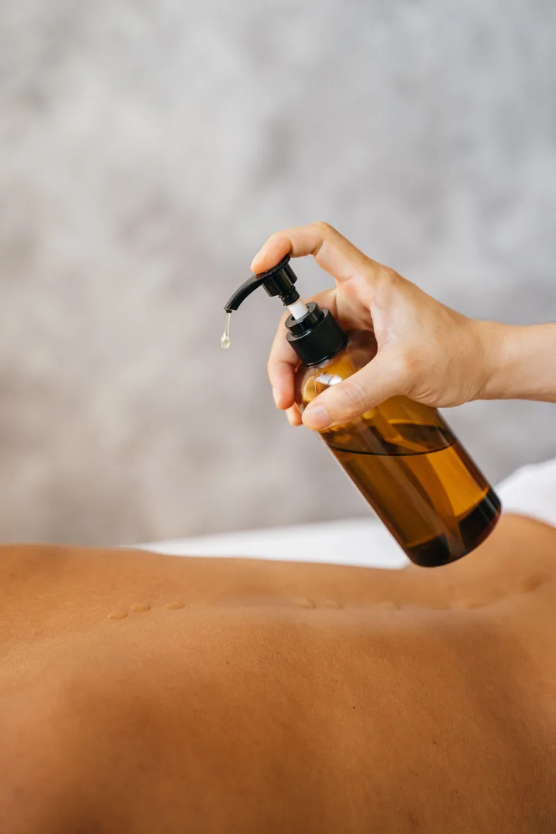 Huile de massage versée sur le dos avant un massage ayurvédique